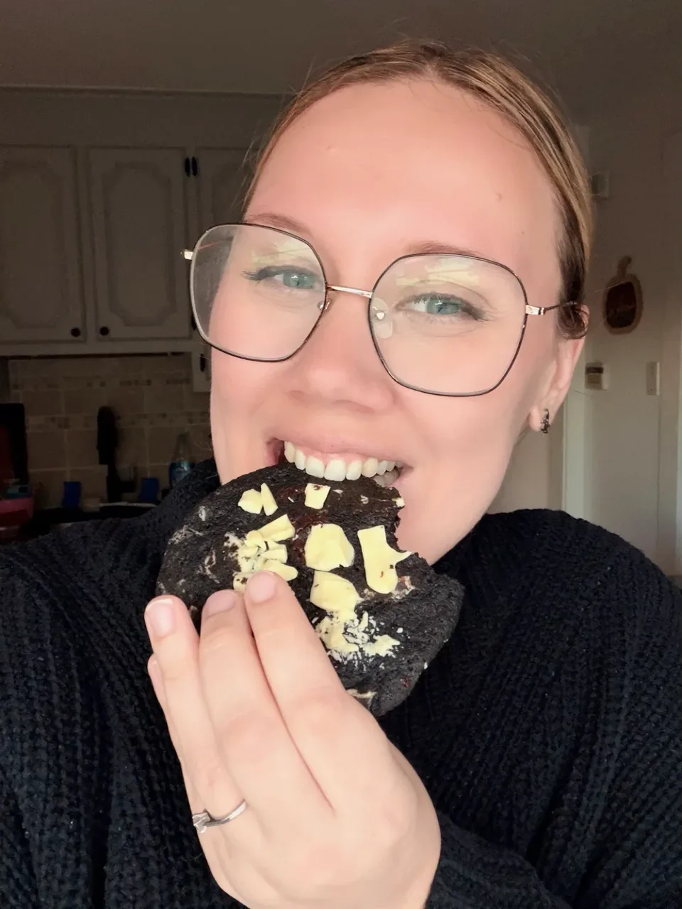 Taking a bite of a triple chocolate cookie topped with white chocolate.